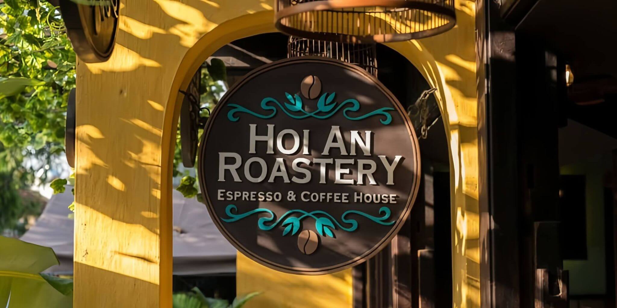 Das runde Schild von Hoi An Roastery unter einem gelben Torbogen in Hoi An